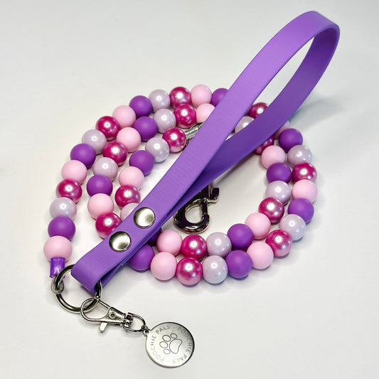 Purple and pink beaded Dog lead with a metal clasp on a white background