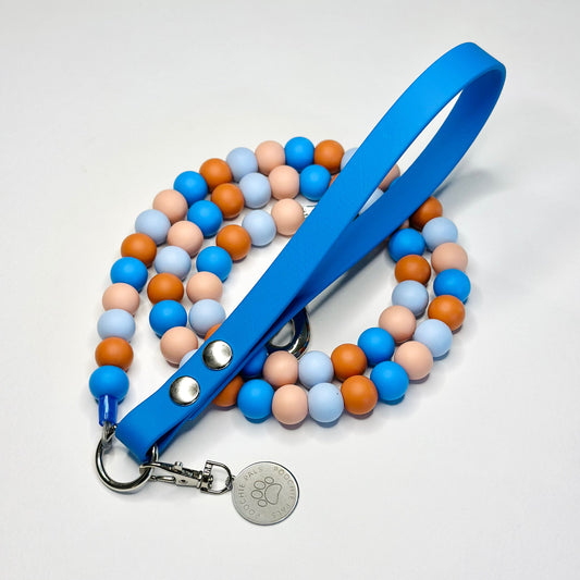Colorful beaded dog leash with a blue handle on a white background
