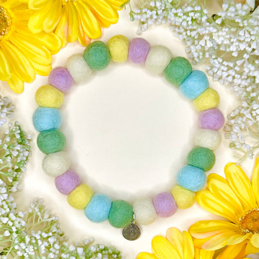 Colorful beaded pom pom dog collar with a charm on a floral background