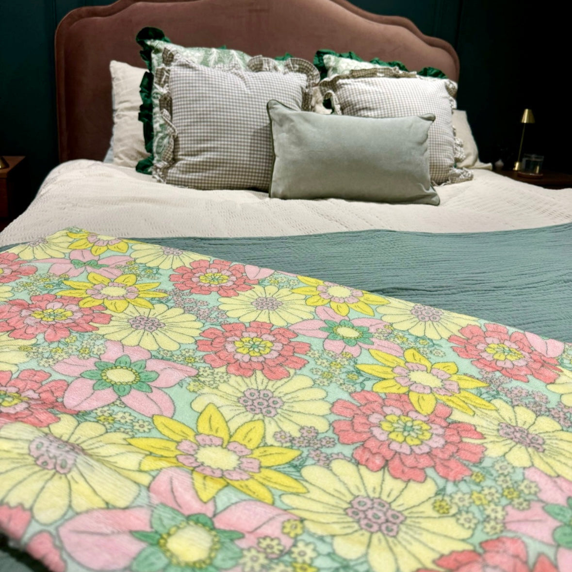 Bed with floral comforter and patterned pillows against a dark paneled wall.